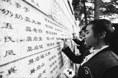 南京大学生志愿者为哭墙上死难同胞姓名描红