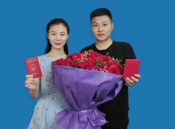 肖志明和徐佳其捧着鲜红的玫瑰花,手持结婚证幸福留影.