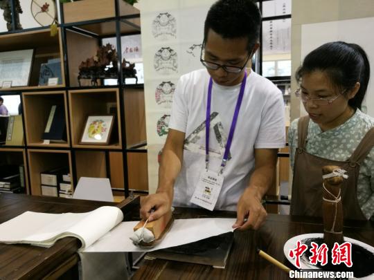 参观者在手工艺人的指导下体验传统的版画印刷过程。　钟升　摄